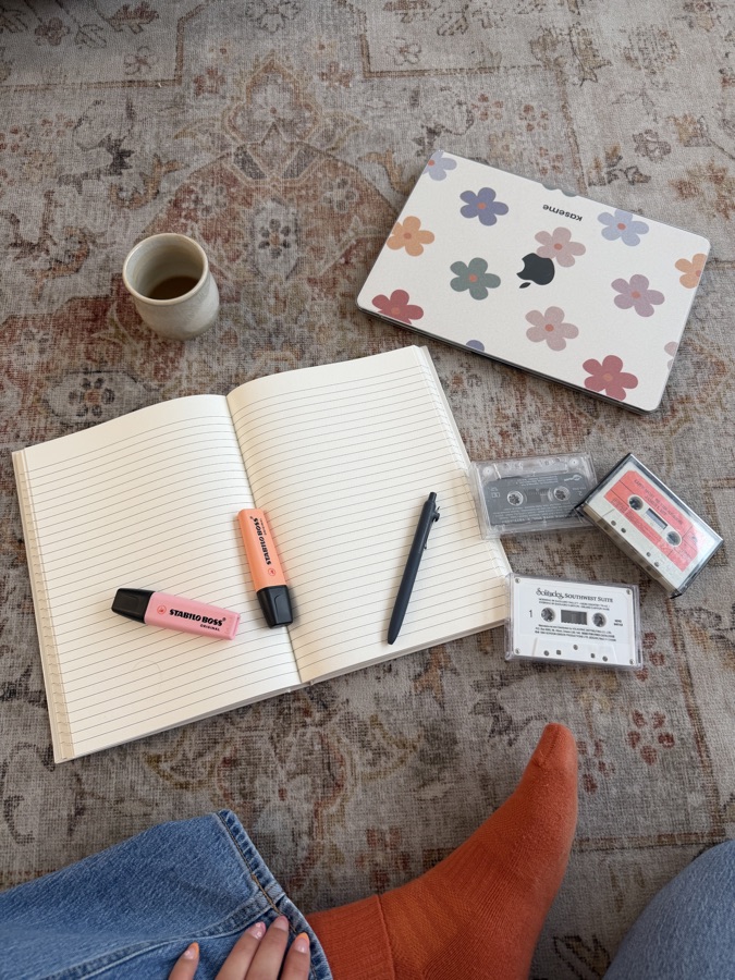 Carnet ouvert, cassettes, surligneurs et café posés sur un tapis
